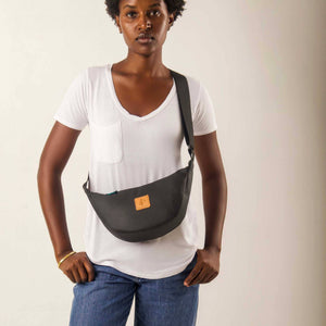 Black vegan leather round shoulder bag by Ecodunia with Kenyan fabric lining, compact crossbody style, and adjustable strap.