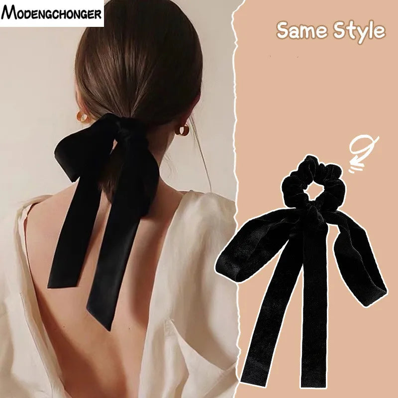 Black velvet bow scrunchie by Hot Trend Vault with vintage style, elastic hair tie for women and girls, shown wrapped around hair.